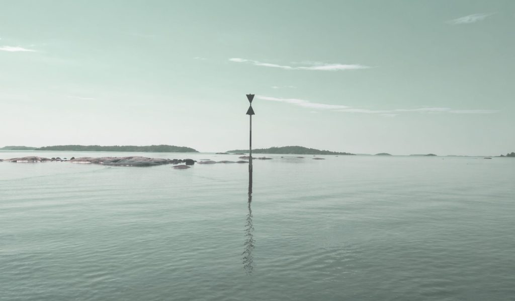 Ett sjömärke som står i vattnet, med lugn havsyta runtom.